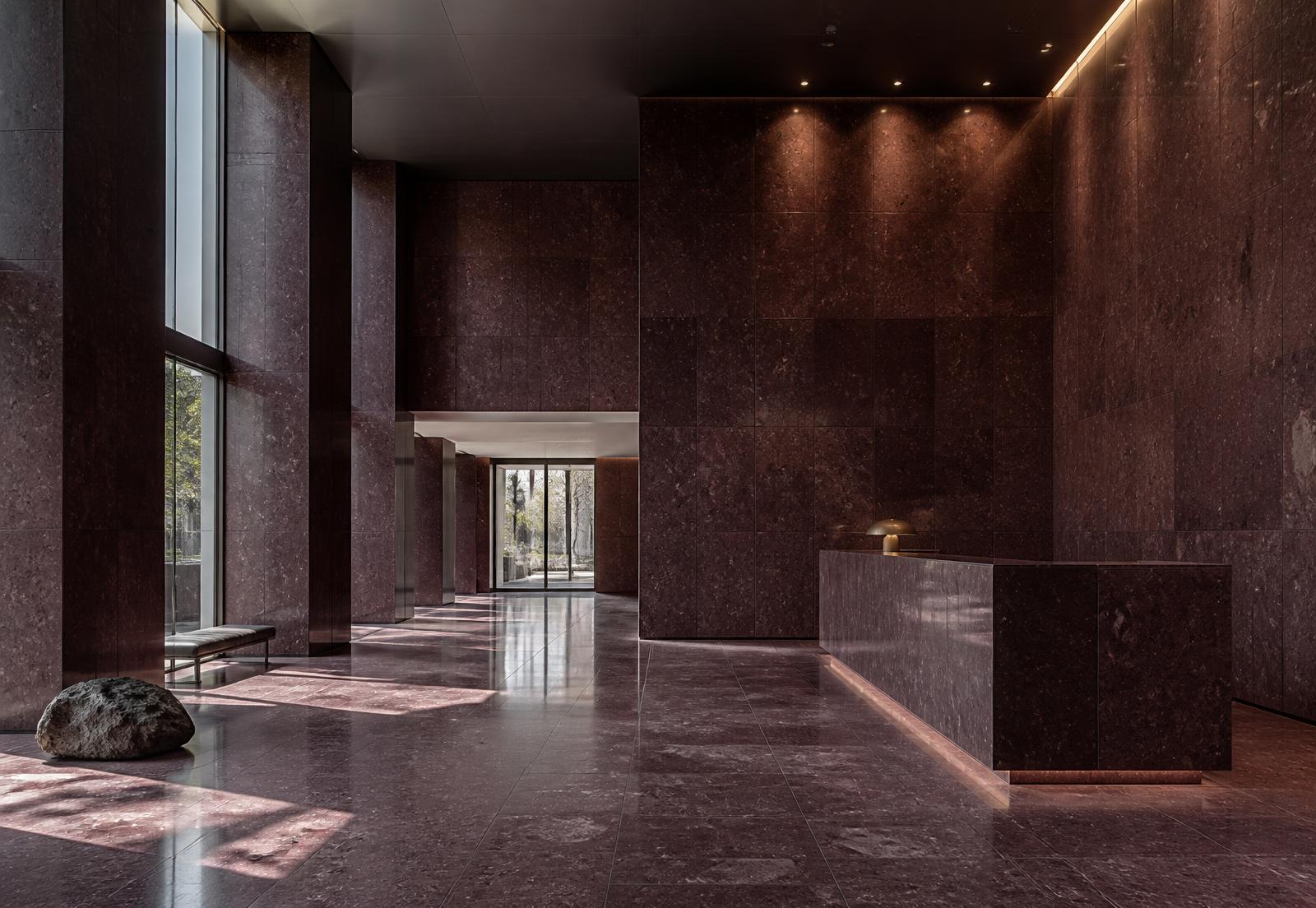 Commercial lobby with polished Shahabad Maroon limestone floor and wall cladding under raking daylight