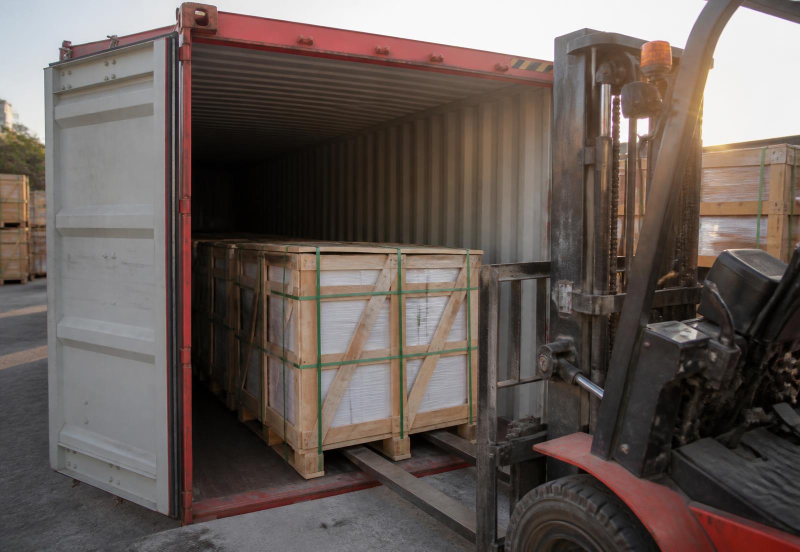 Twenty foot shipping container part loaded with strapped timber crates of stone tiles