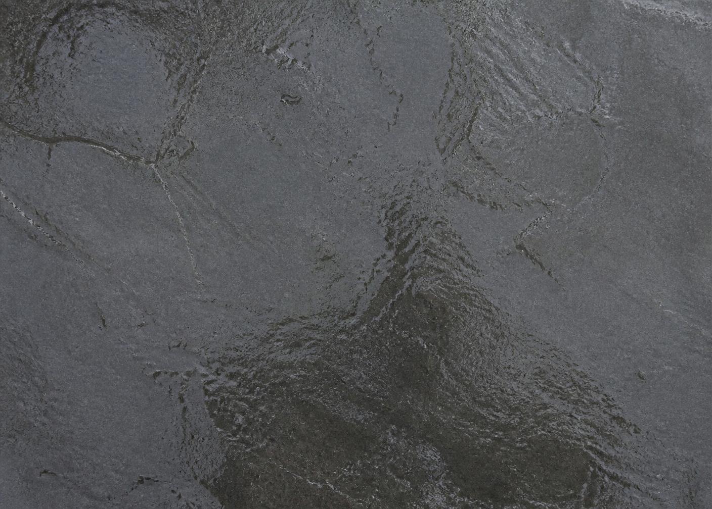 Honed Shahabad Grey limestone slab with water on the surface, showing the darker charcoal wet tone